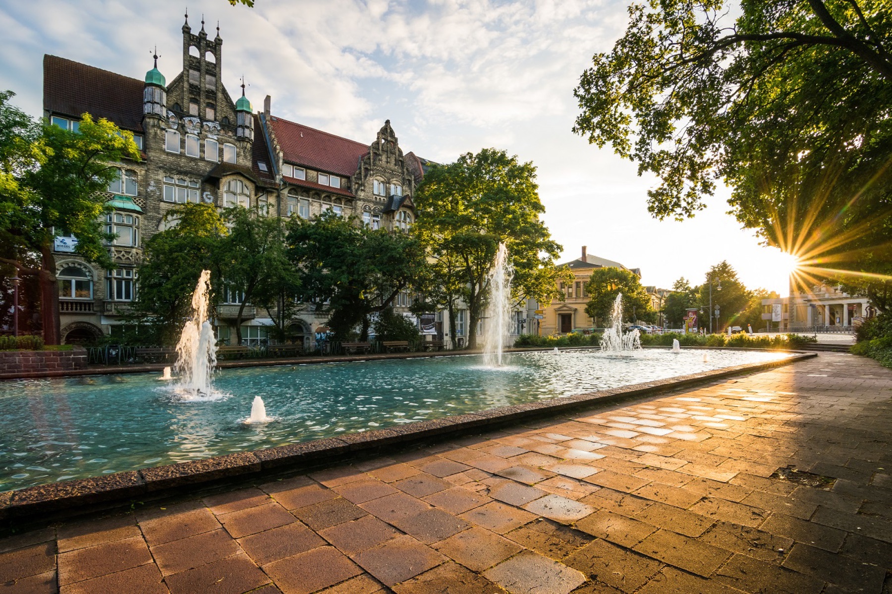 Platz mit Brunnen und historischer Bebauung im Abendlicht