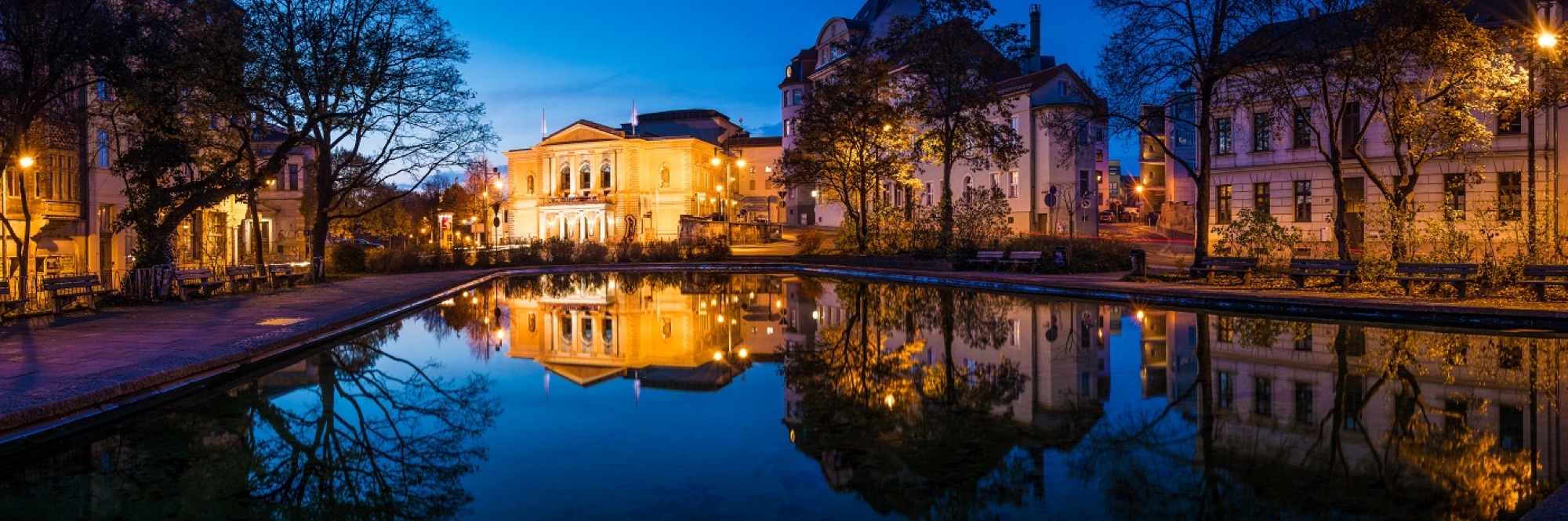 Beleuchtetes Gebäude mit Spiegelung im Wasser am Abend